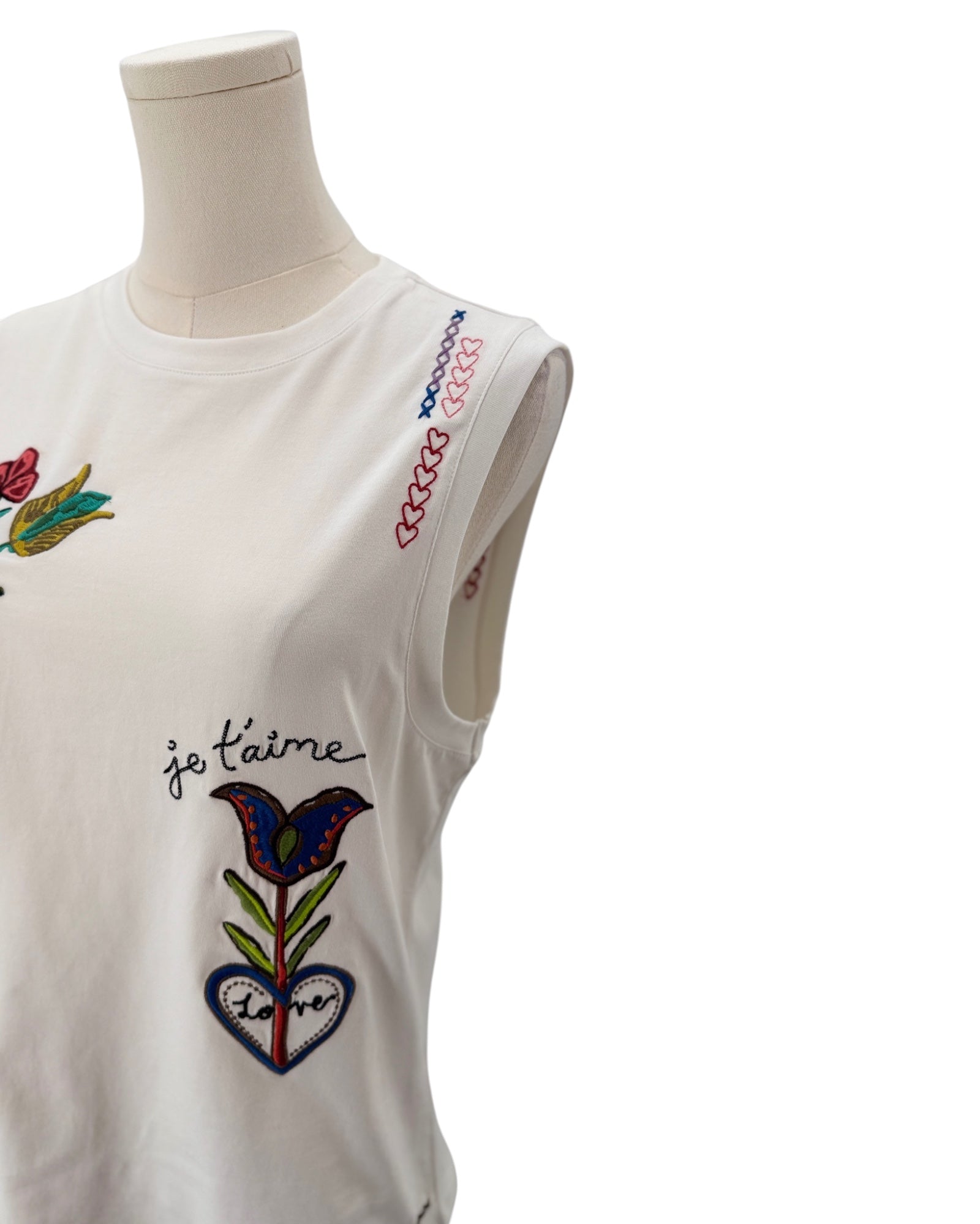 White sleeveless top with colorful embroidery on a mannequin against a white background