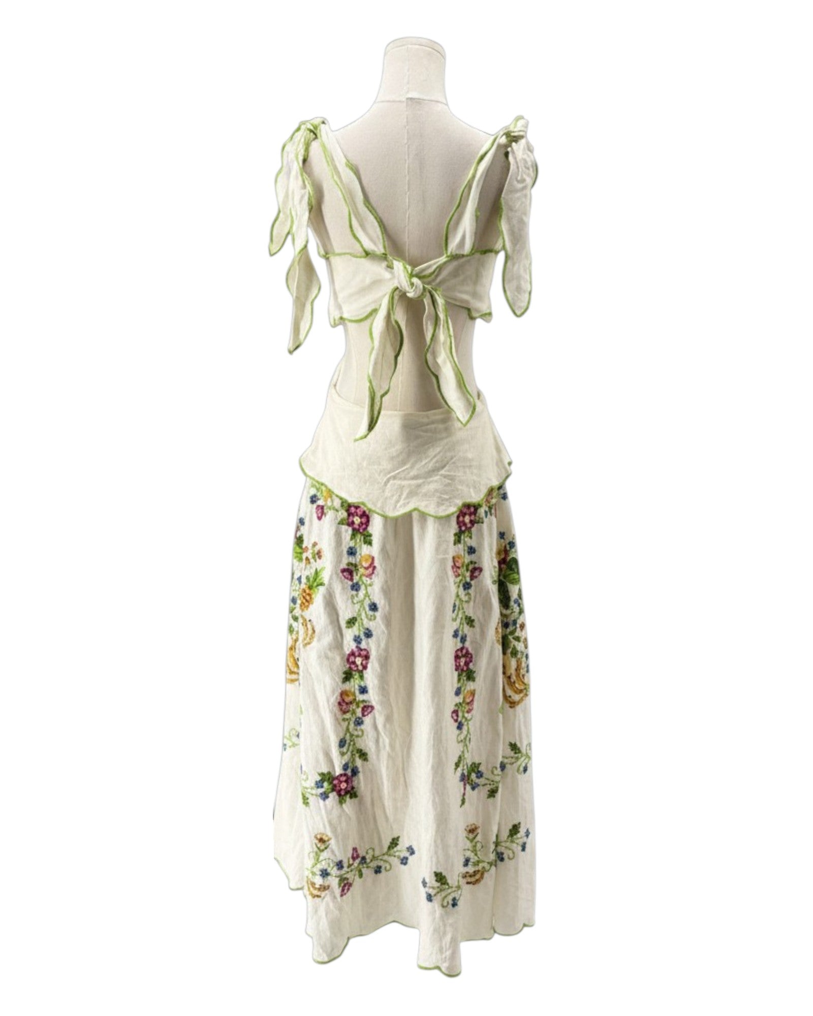 Mannequin wearing a white dress with floral patterns and green accents on a white background