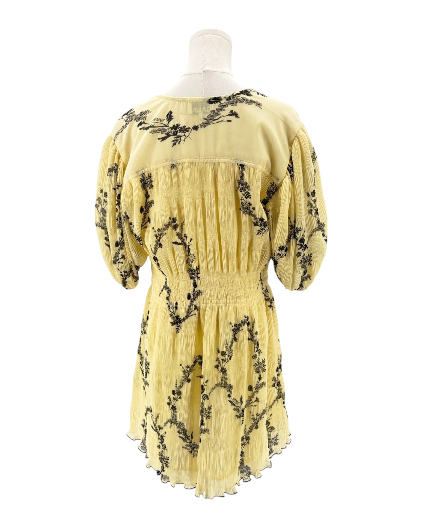 Yellow dress with black floral patterns on a mannequin against a white background