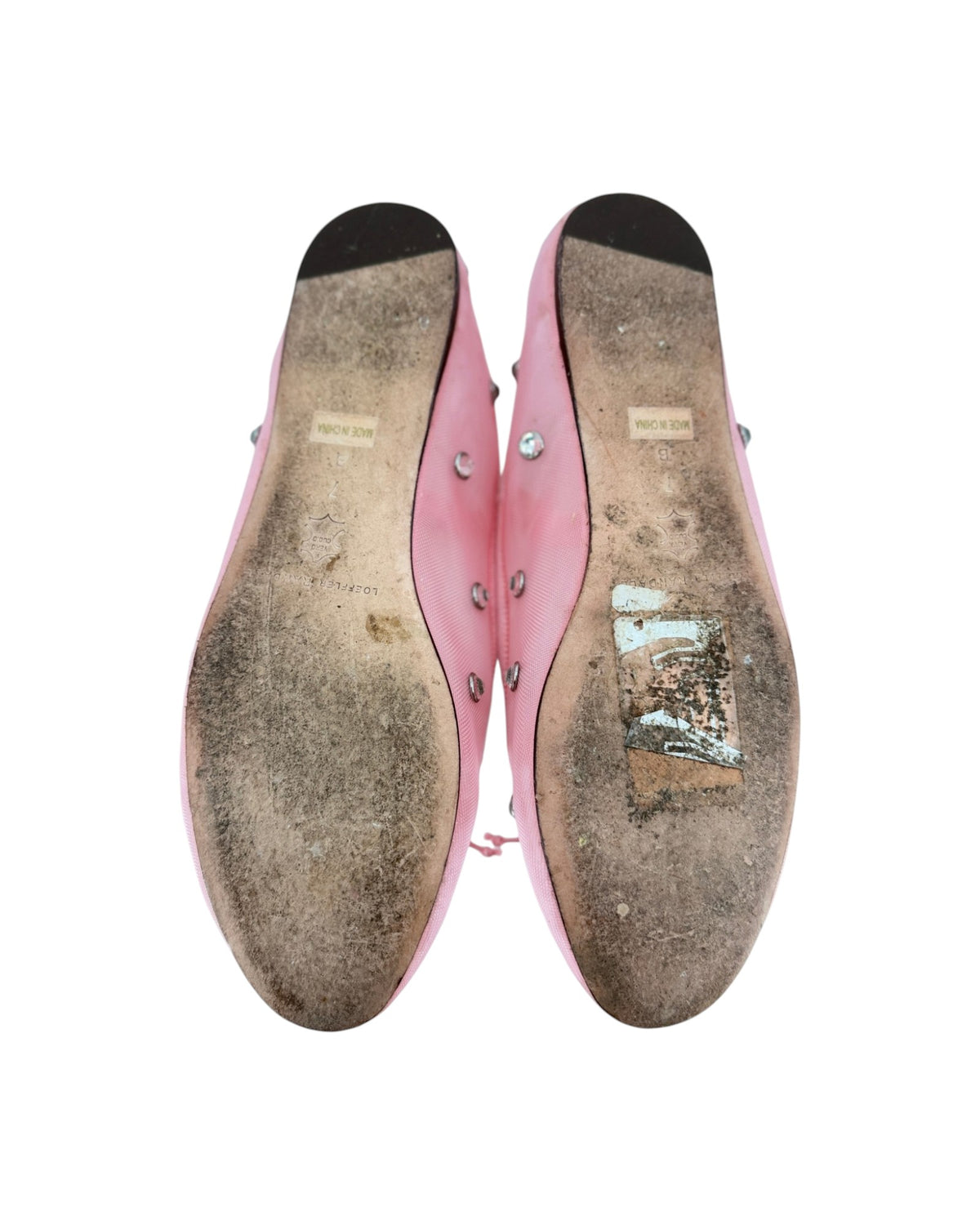 Pink ballet flats with attached jewels and an elastic strap across the top on a white bacground