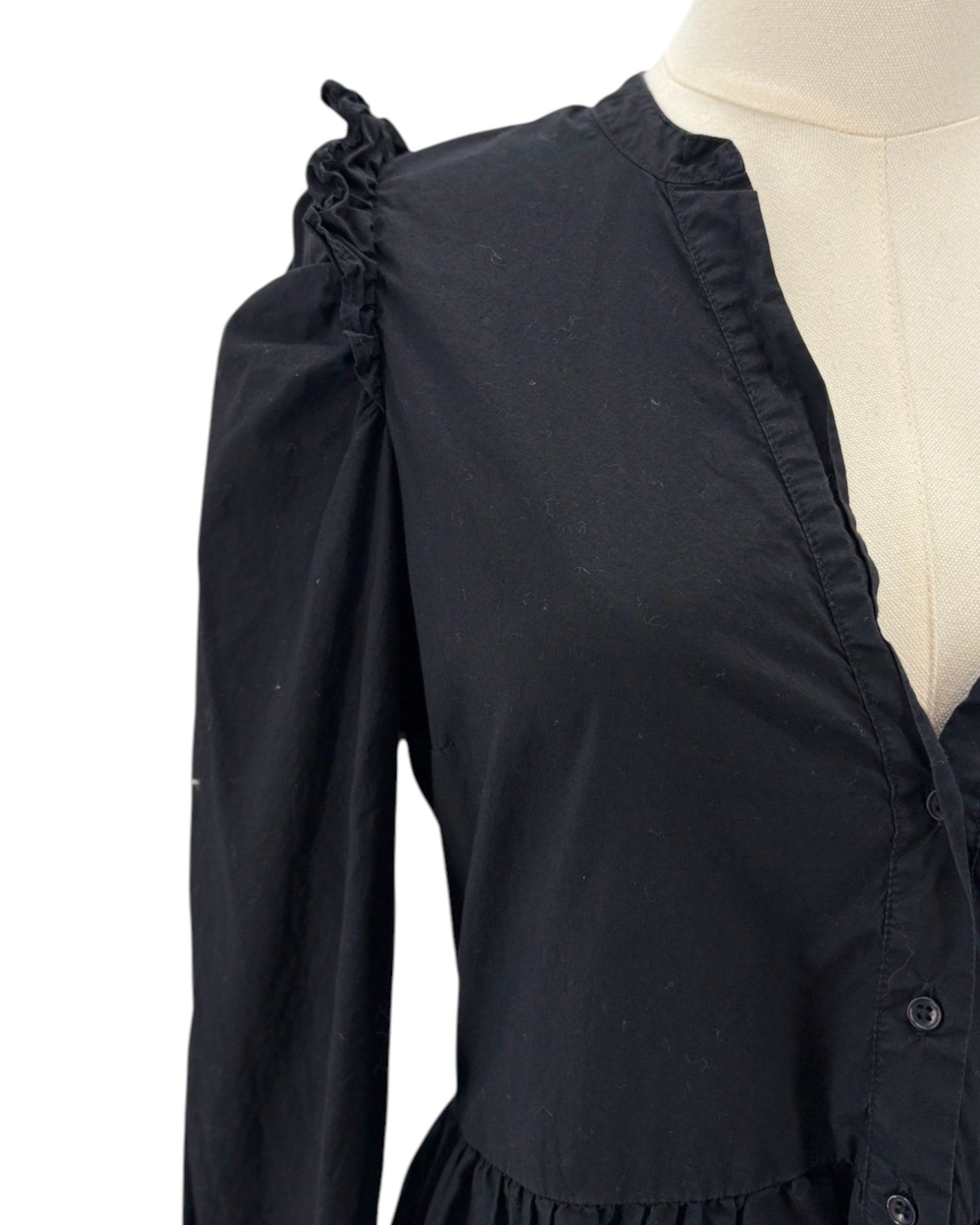 nation LA black dress with ruffled shoulders on a mannequin against a white background