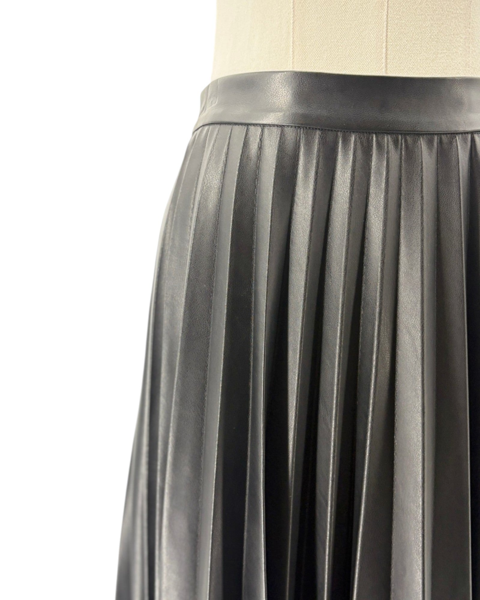 Black pleated skirt on a mannequin against a white background