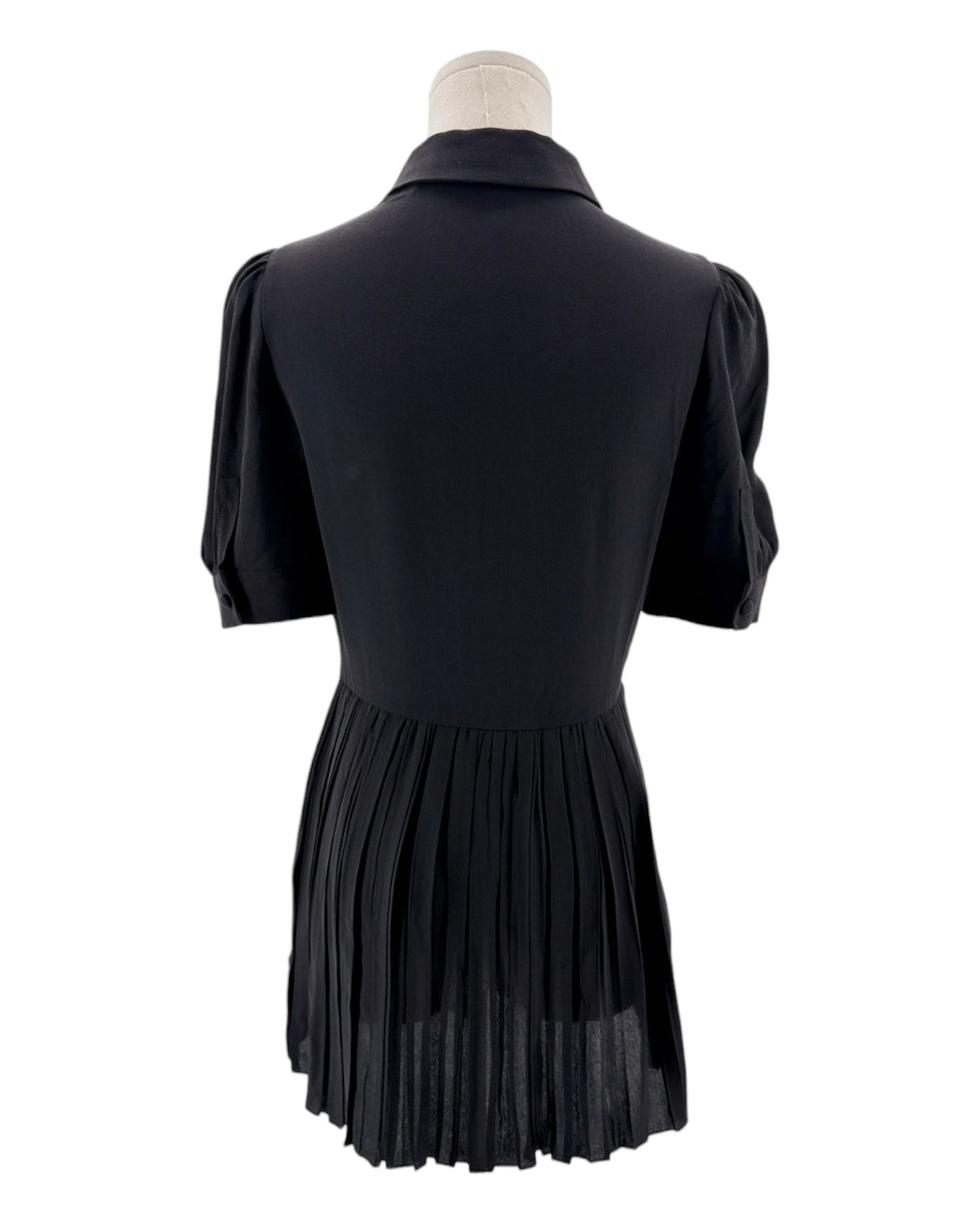 Black pleated dress on a mannequin against a white background