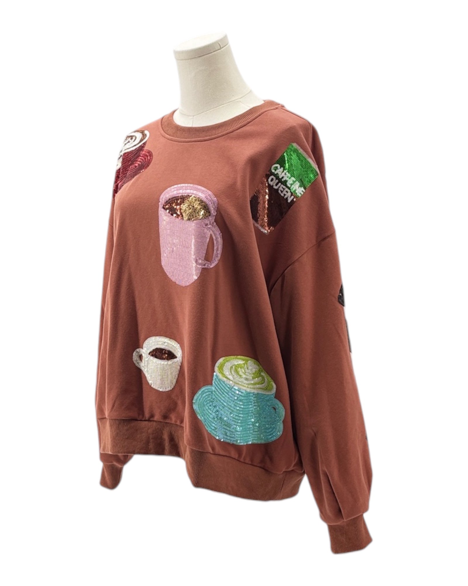 Brown sweatshirt with coffee-themed patches on a mannequin against a white background