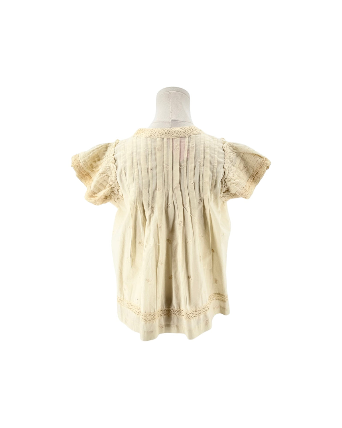 Cream short flutter sleeve blouse with tassel and embroidery details on a mannequin on a white background