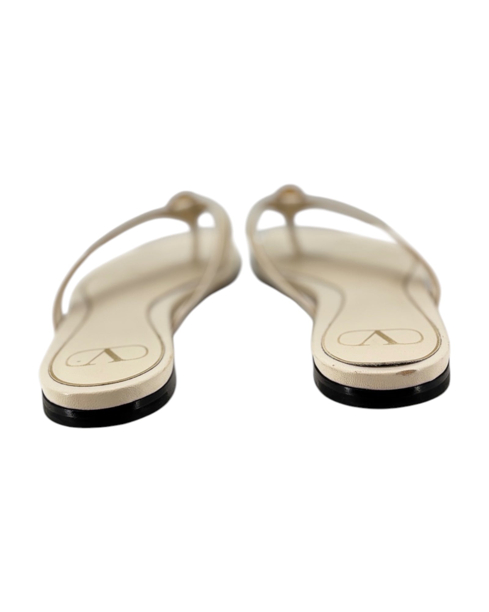 Pair of cream flip-flops with black soles on a white background