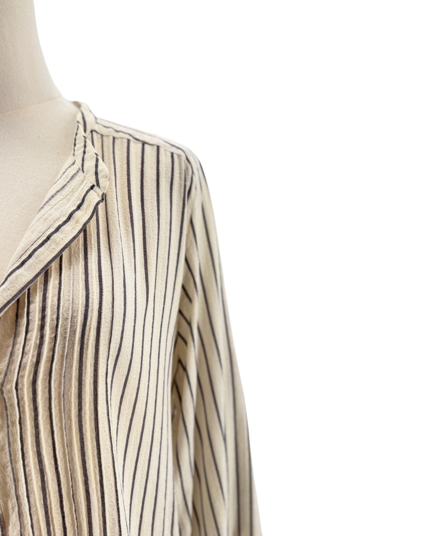 Mannequin wearing a beige and black striped shirt on a white background