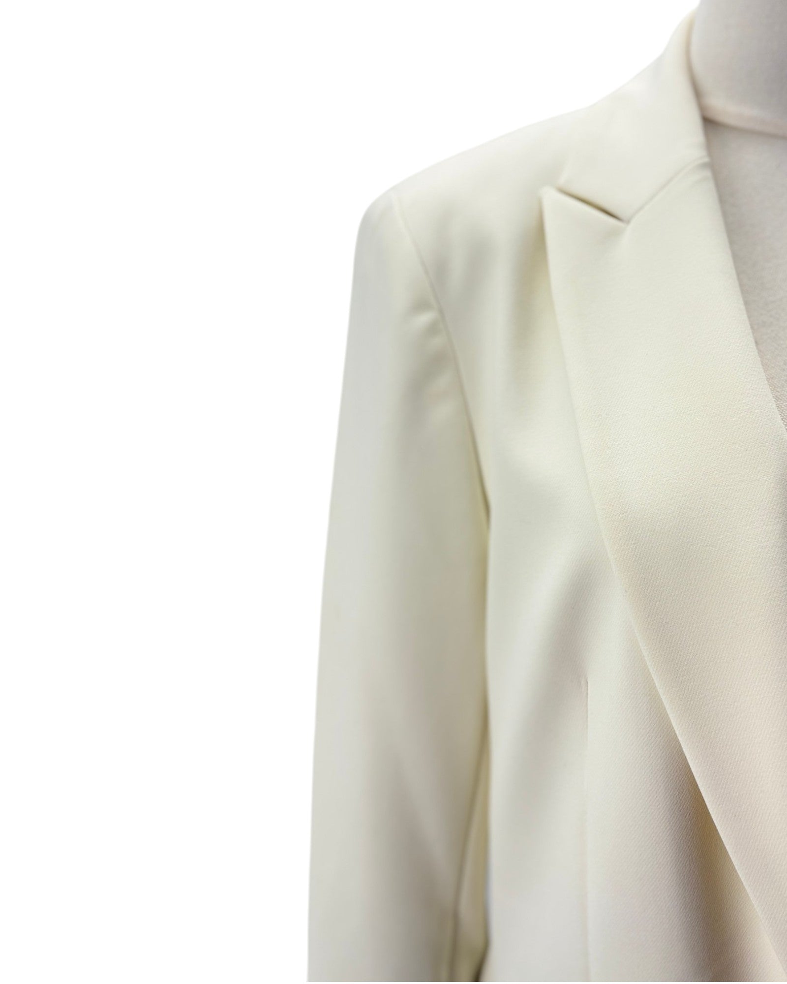 Close-up of a cream-colored blazer jacket on a mannequin torso against a plain white background.