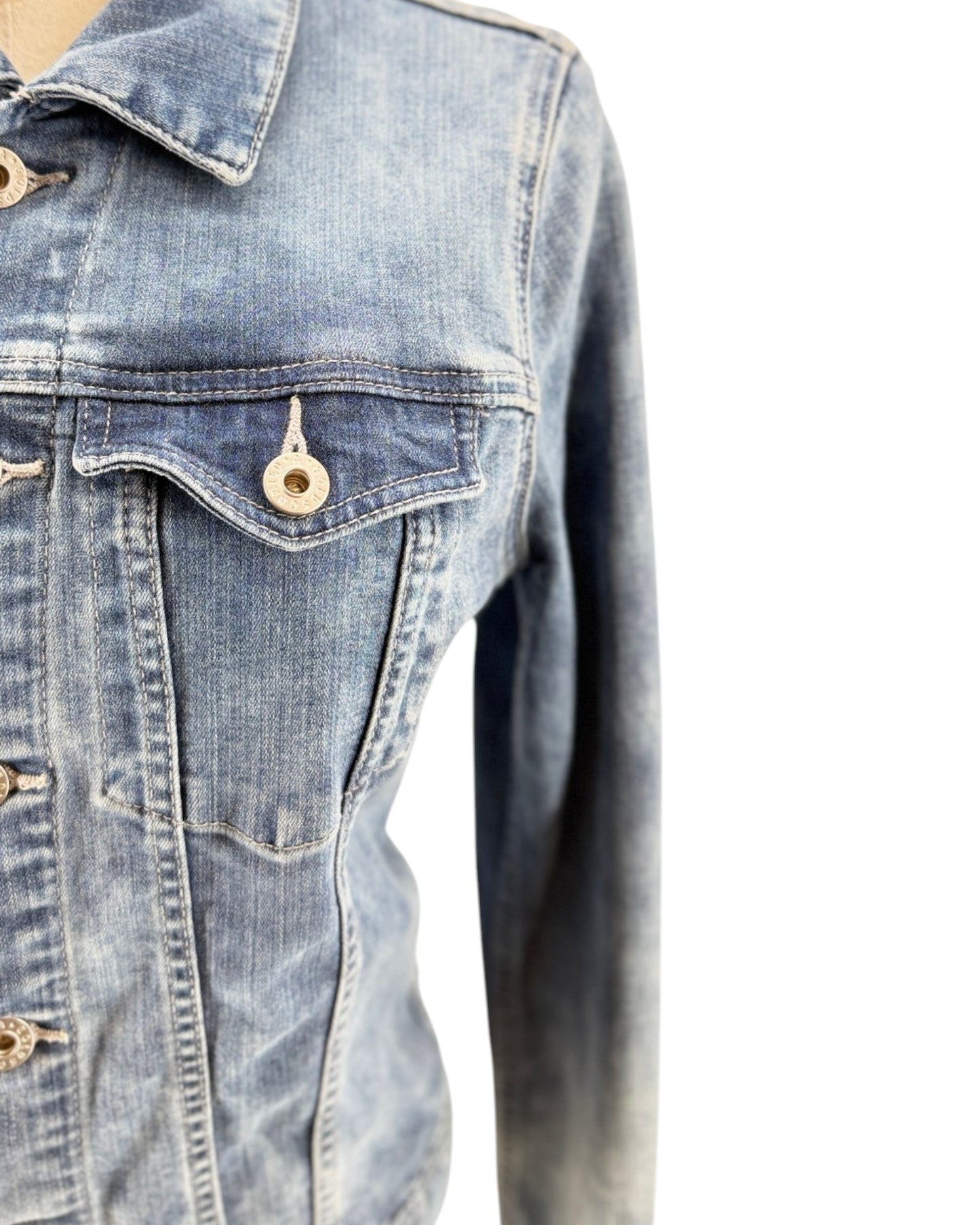 Close-up of a denim jacket with a pocket and button on a white background