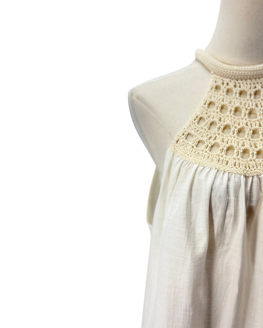 A close-up of a cream-colored linen dress displayed on a mannequin, featuring a high crochet lace neckline.