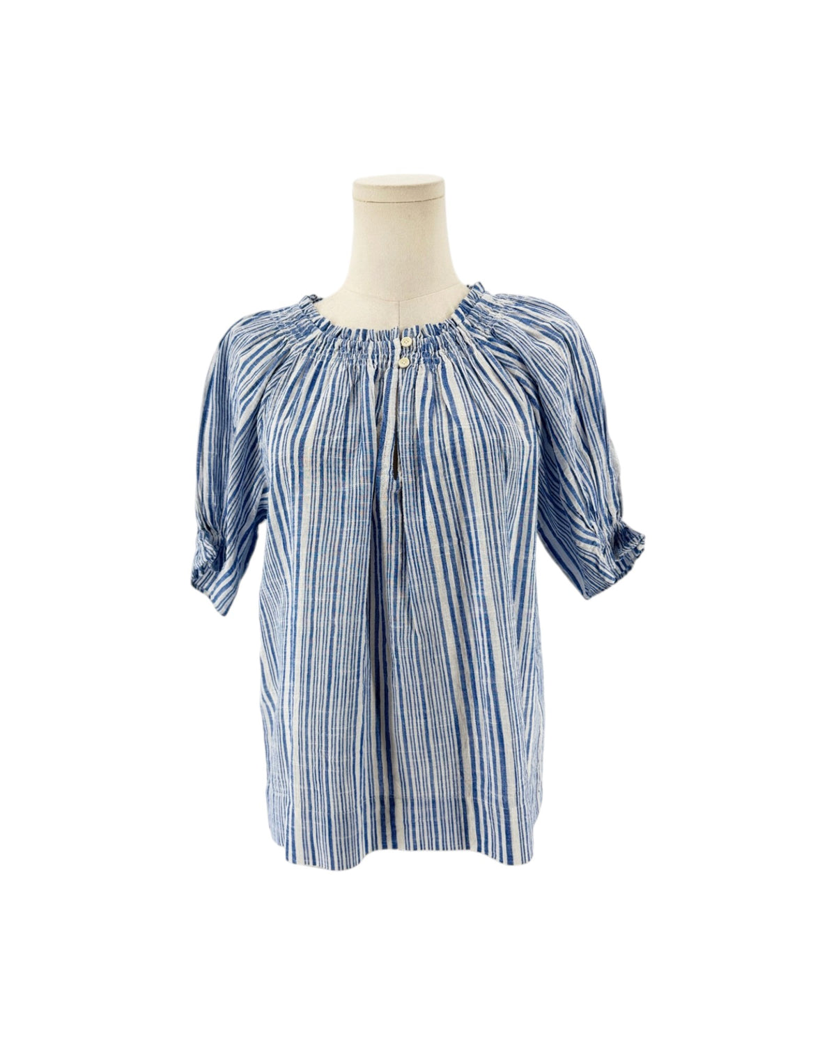 Blue and white gathered smocking at neckline, keyhole opening with button closure, dolman puff sleeve with gathered ruffle at cuff on a mannequin on a white background