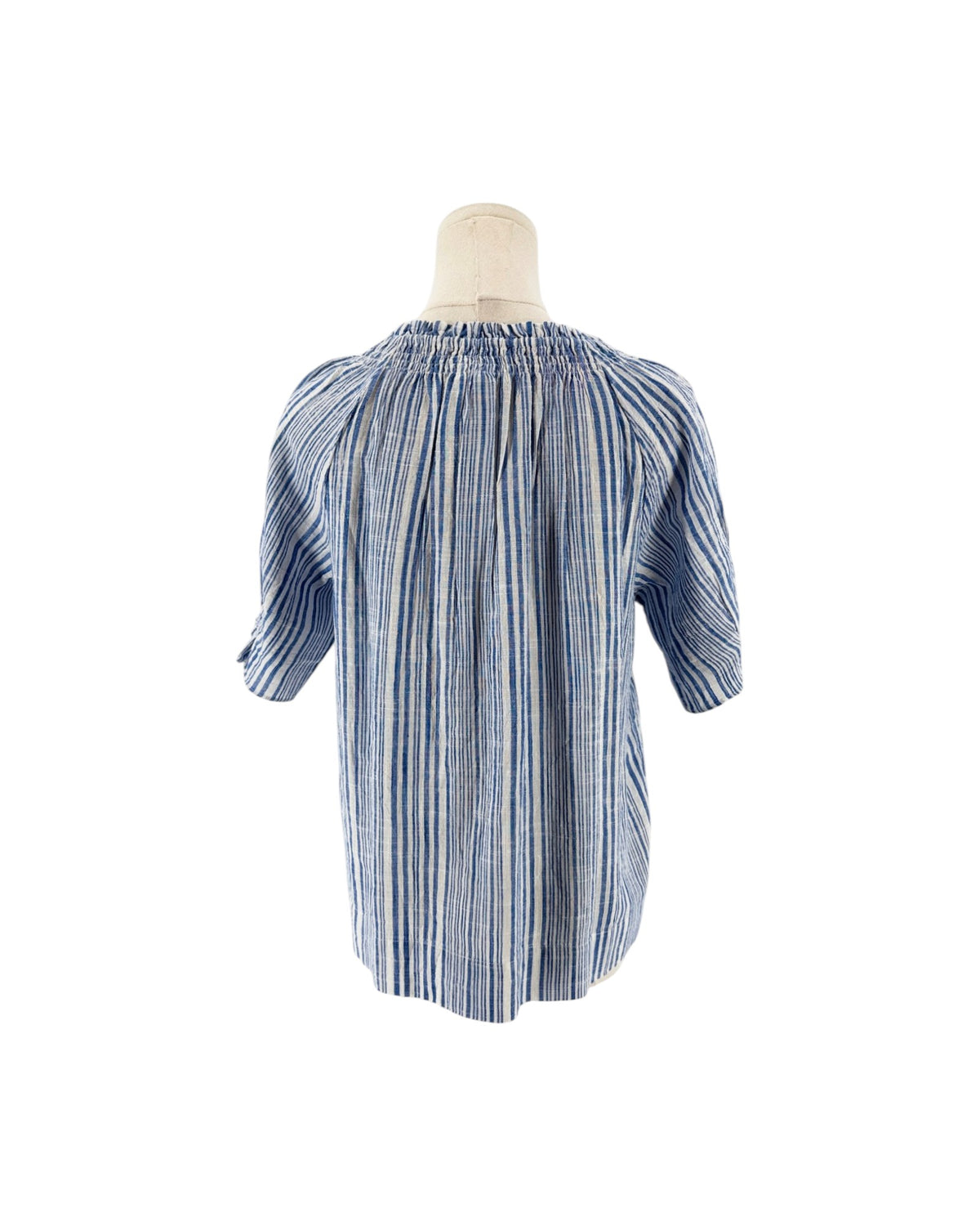 Blue and white gathered smocking at neckline, keyhole opening with button closure, dolman puff sleeve with gathered ruffle at cuff on a mannequin on a white background