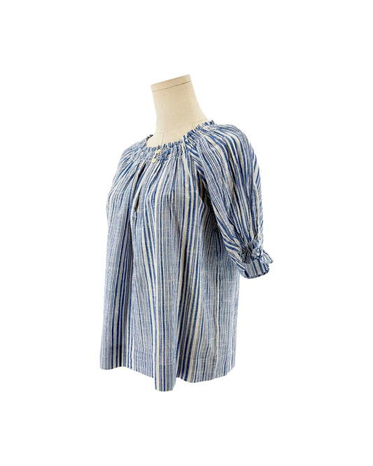 Blue and white gathered smocking at neckline, keyhole opening with button closure, dolman puff sleeve with gathered ruffle at cuff on a mannequin on a white background