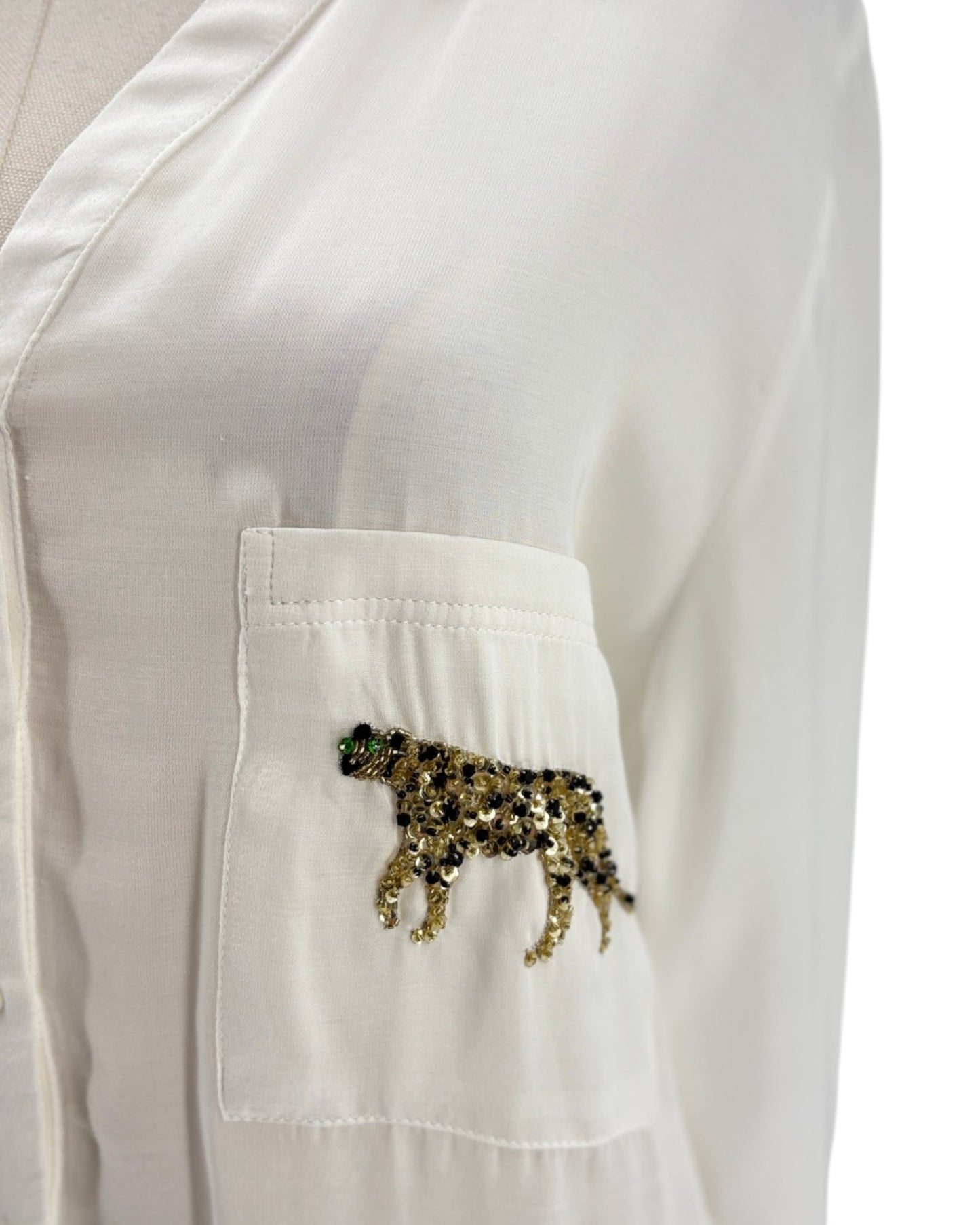 White shirt with a sequined panther design on the chest pocket against a white background