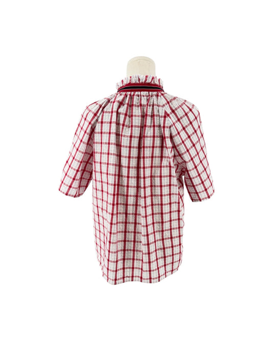 Red and white checkered with metallic threads short sleeve, side slits, split v-neckline, high ruffled collar trimmed with contrasting multi-colored striped ribbon on a mannequin on a white background