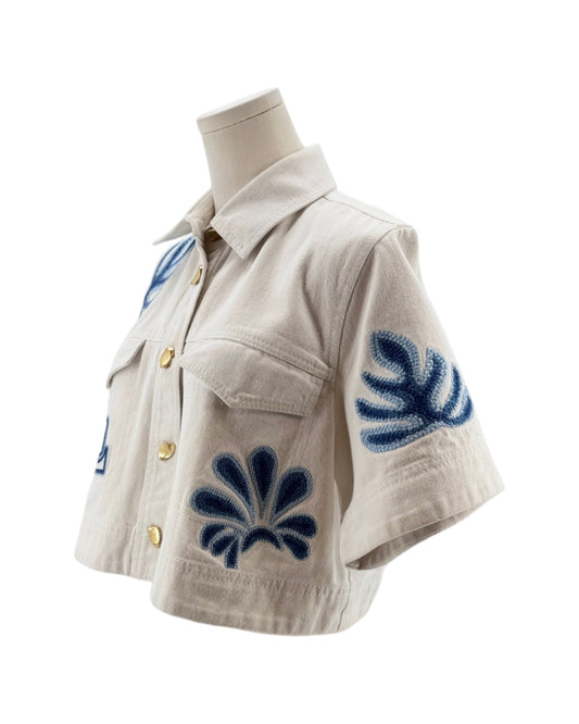 White jacket with blue floral patterns on a mannequin against a white background