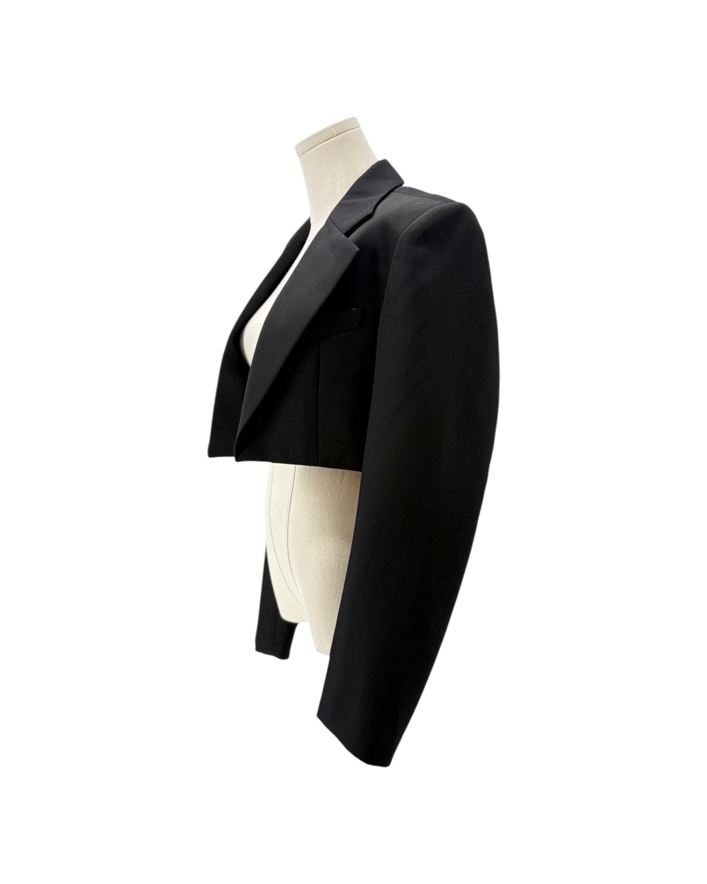 A black cropped blazer jacket displayed on a cream-colored mannequin torso against a solid white background.