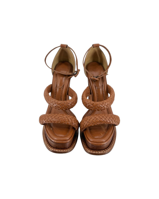 A pair of brown leather strappy sandals with braided straps and low block heels, shown from a top-down view on a white background.