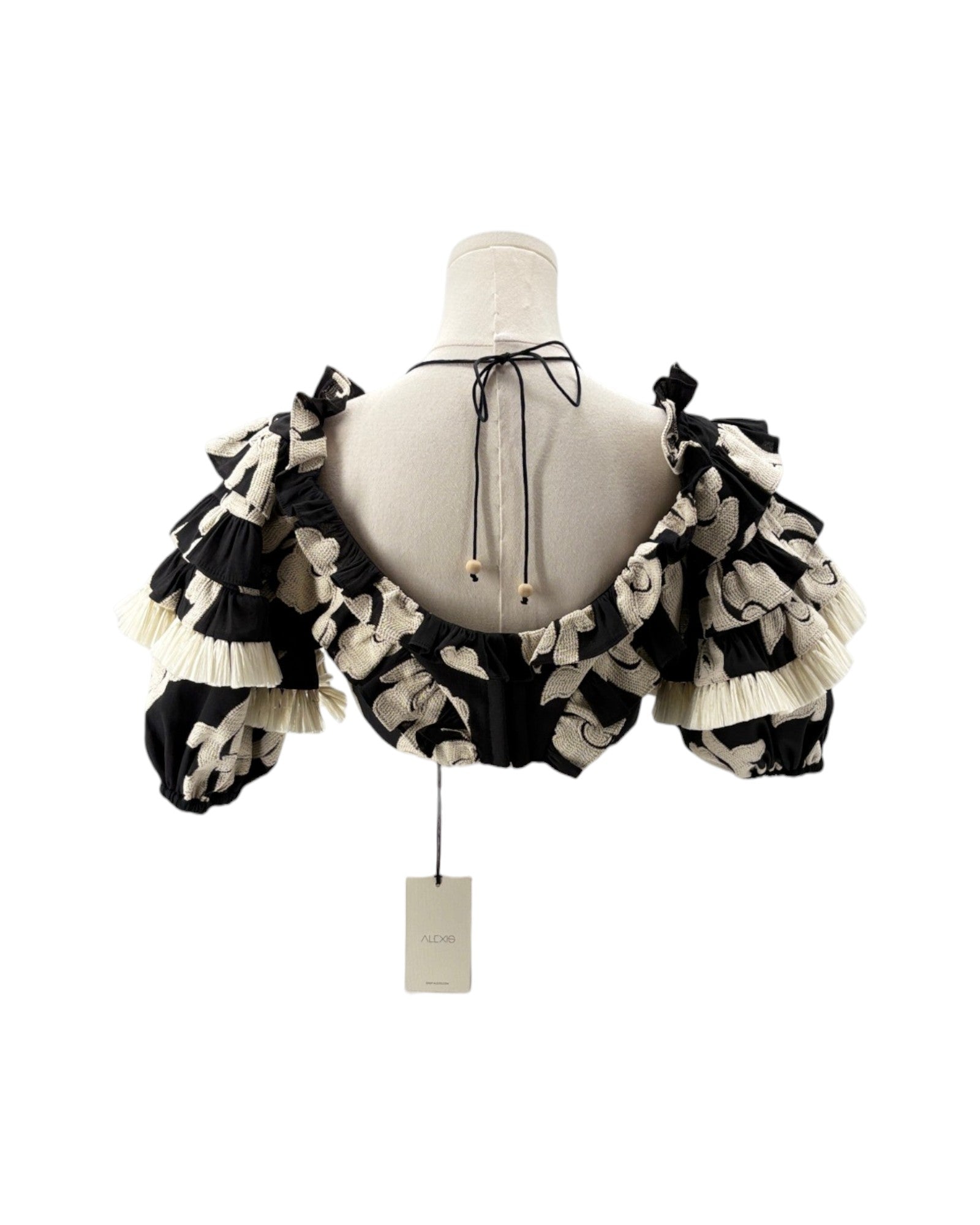 Black and white ruffled top on a mannequin with a tag against a white background