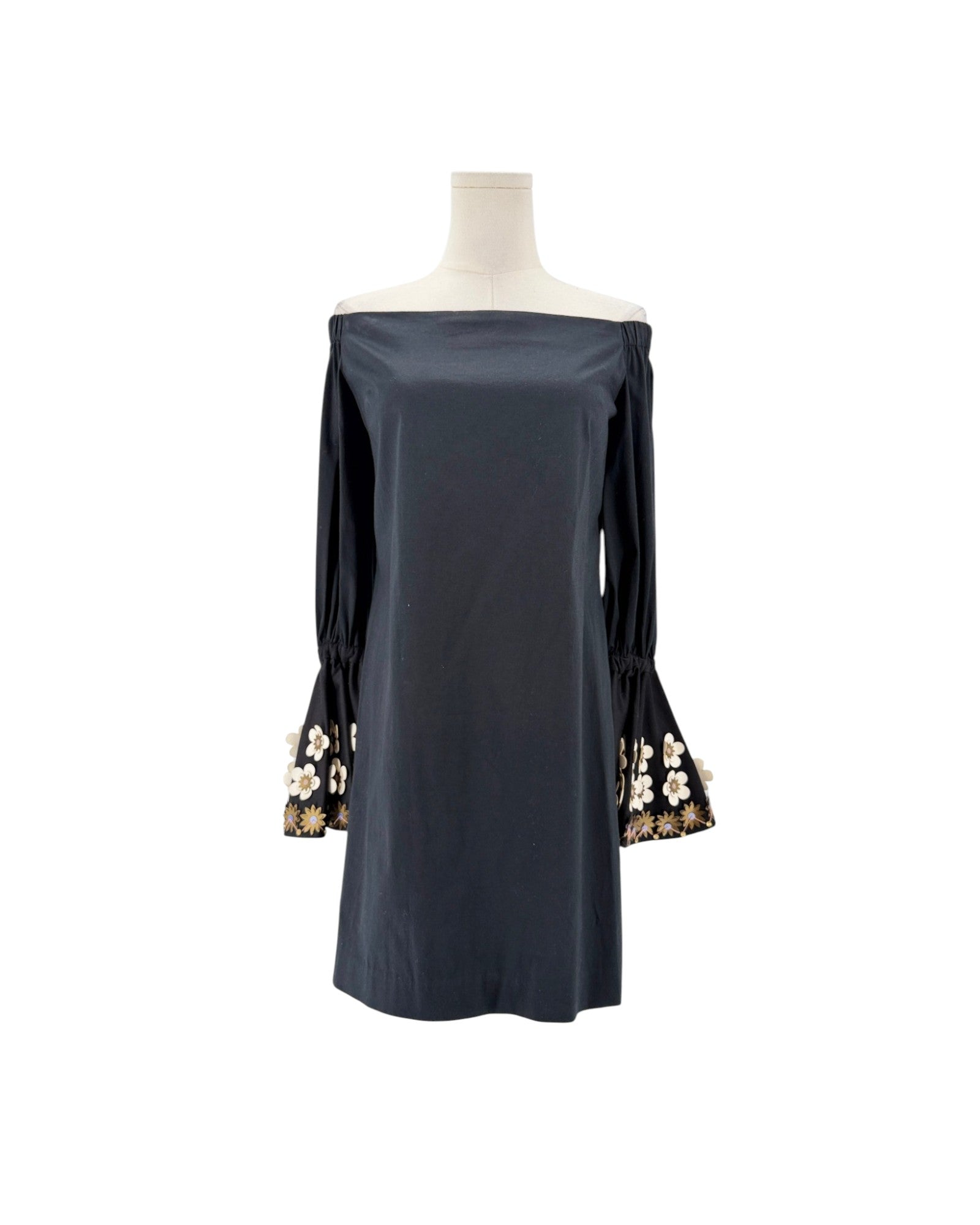 A dark navy blue off-the-shoulder dress displayed on a mannequin torso against a plain white background. The dress features long sleeves with gathered cuffs decorated with gold and white floral embroidery.