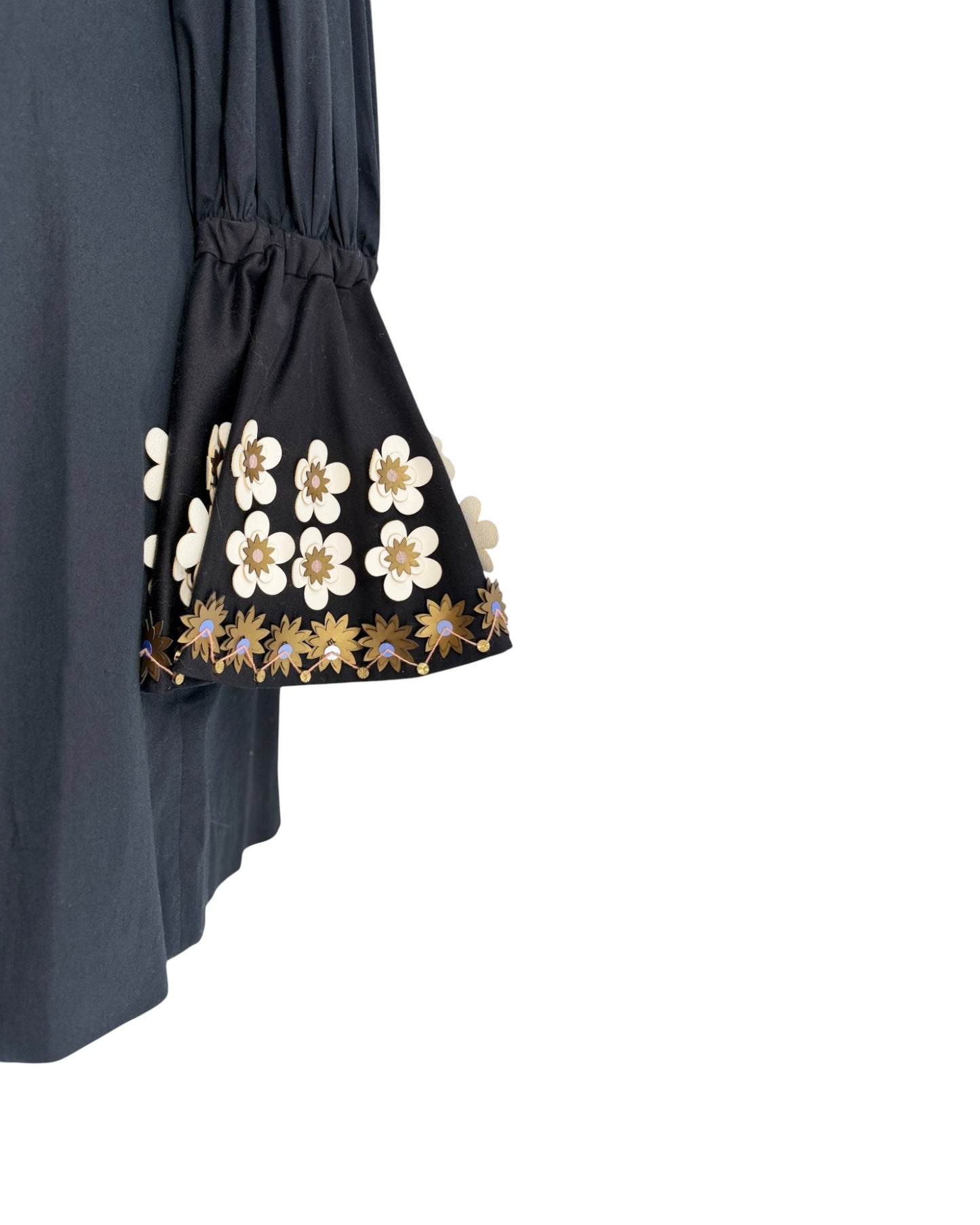 Close-up of a dark navy blue dress or tunic with a gathered elastic waist and flared bell sleeves, featuring white and gold floral embroidery along the sleeve cuffs.