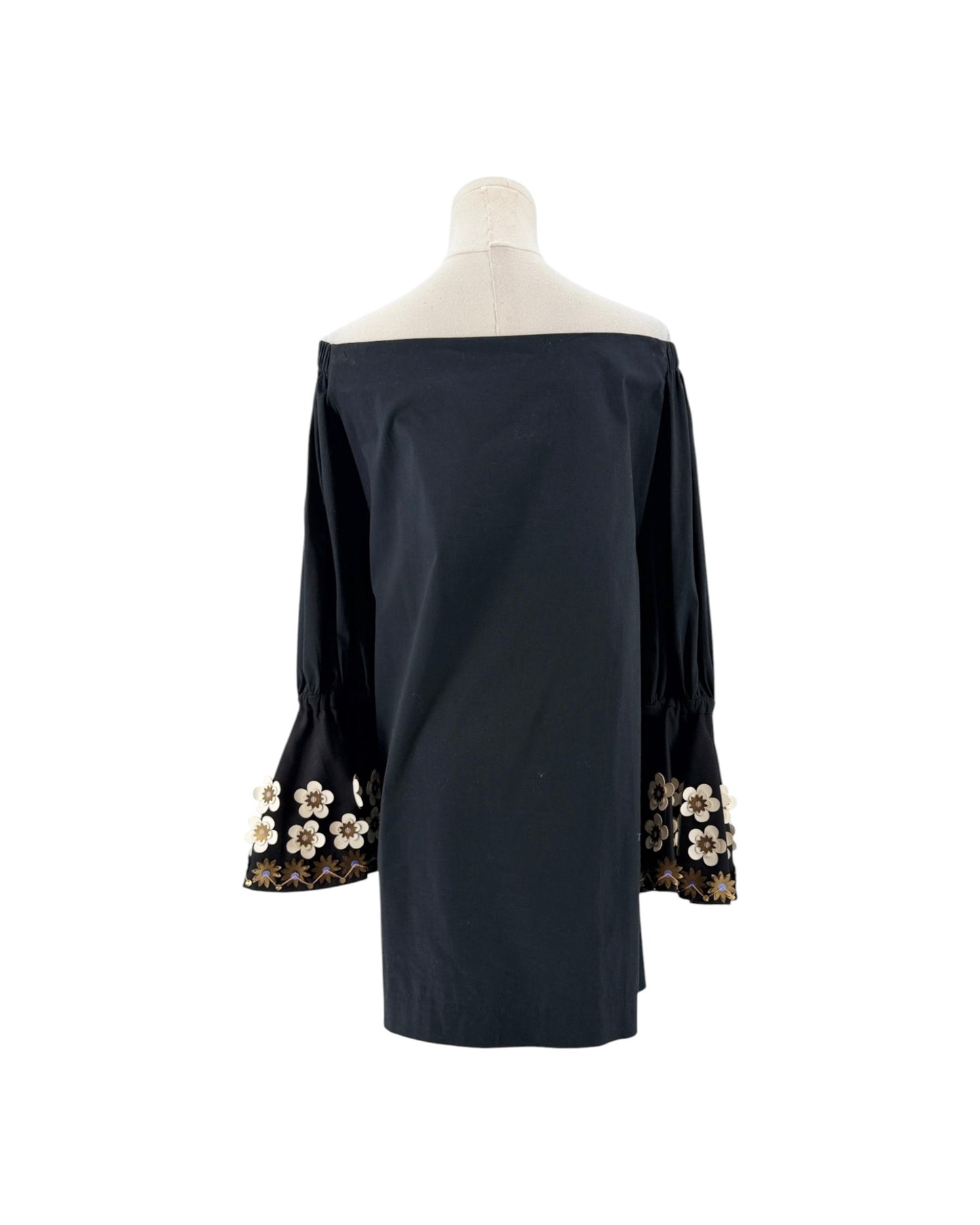 A black off-the-shoulder long-sleeve blouse displayed on a mannequin torso, featuring decorative floral lace and bead trim at the cuffs.