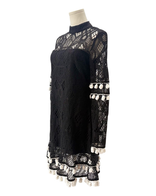 Black lace dress with white embellishments on a mannequin against a white background
