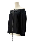 Black off-shoulder top with pearl details on a mannequin against a white background