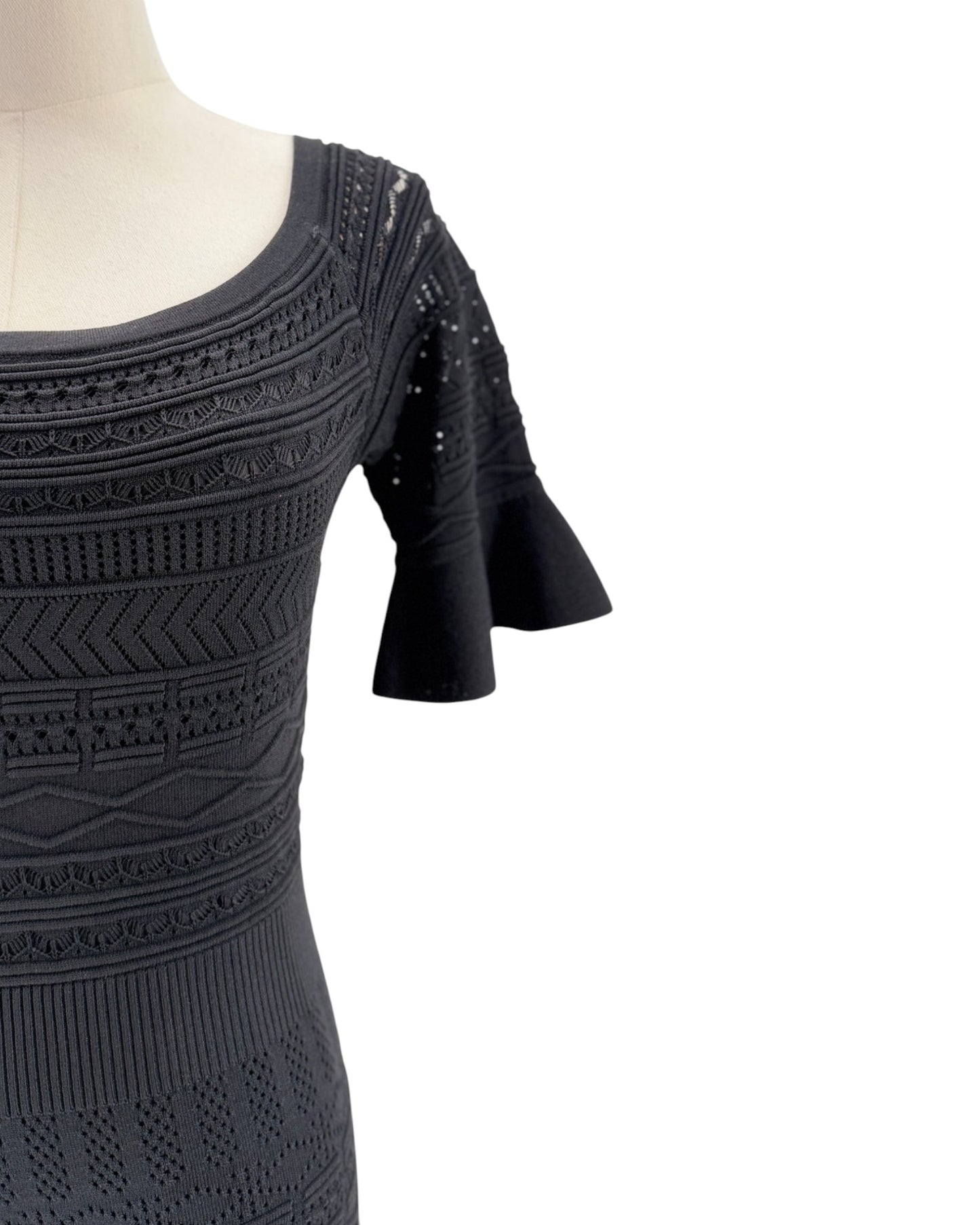 Black dress with intricate patterns on a mannequin against a white background