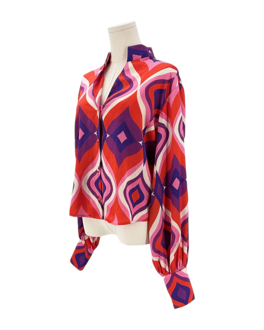 Colorful patterned blouse on a mannequin against a white background