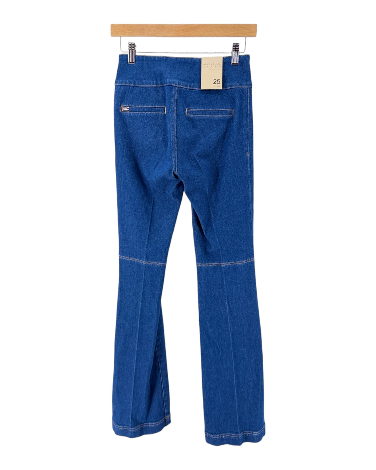 Blue denim flare jeans shown from the back, hanging from a wooden hanger with metal clips against a plain white background.