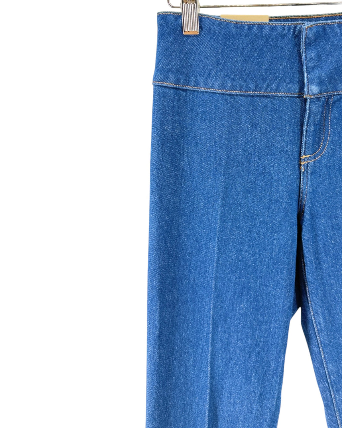 Blue denim flare jeans shown from the back, hanging from a wooden hanger with metal clips against a plain white background.