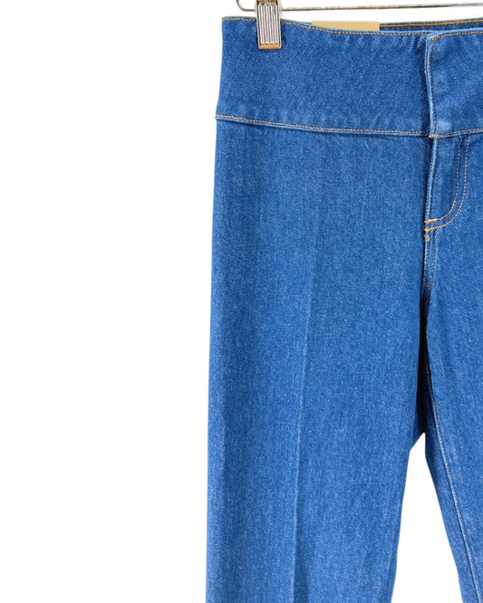 Blue denim flare jeans shown from the back, hanging from a wooden hanger with metal clips against a plain white background.