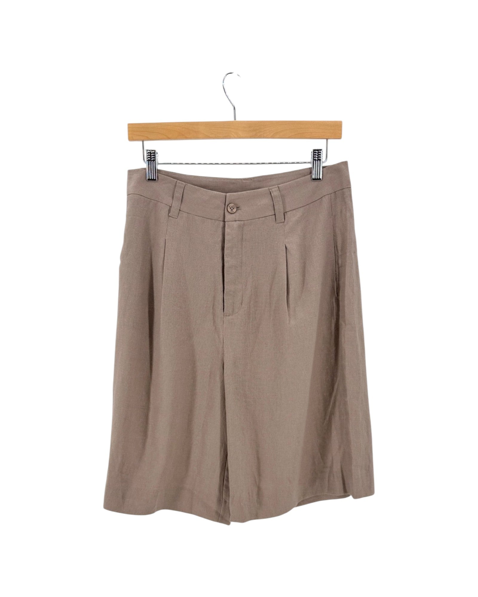 Taupe brown pleated linen short hanging from a wooden hanger with metal clips against a white background.