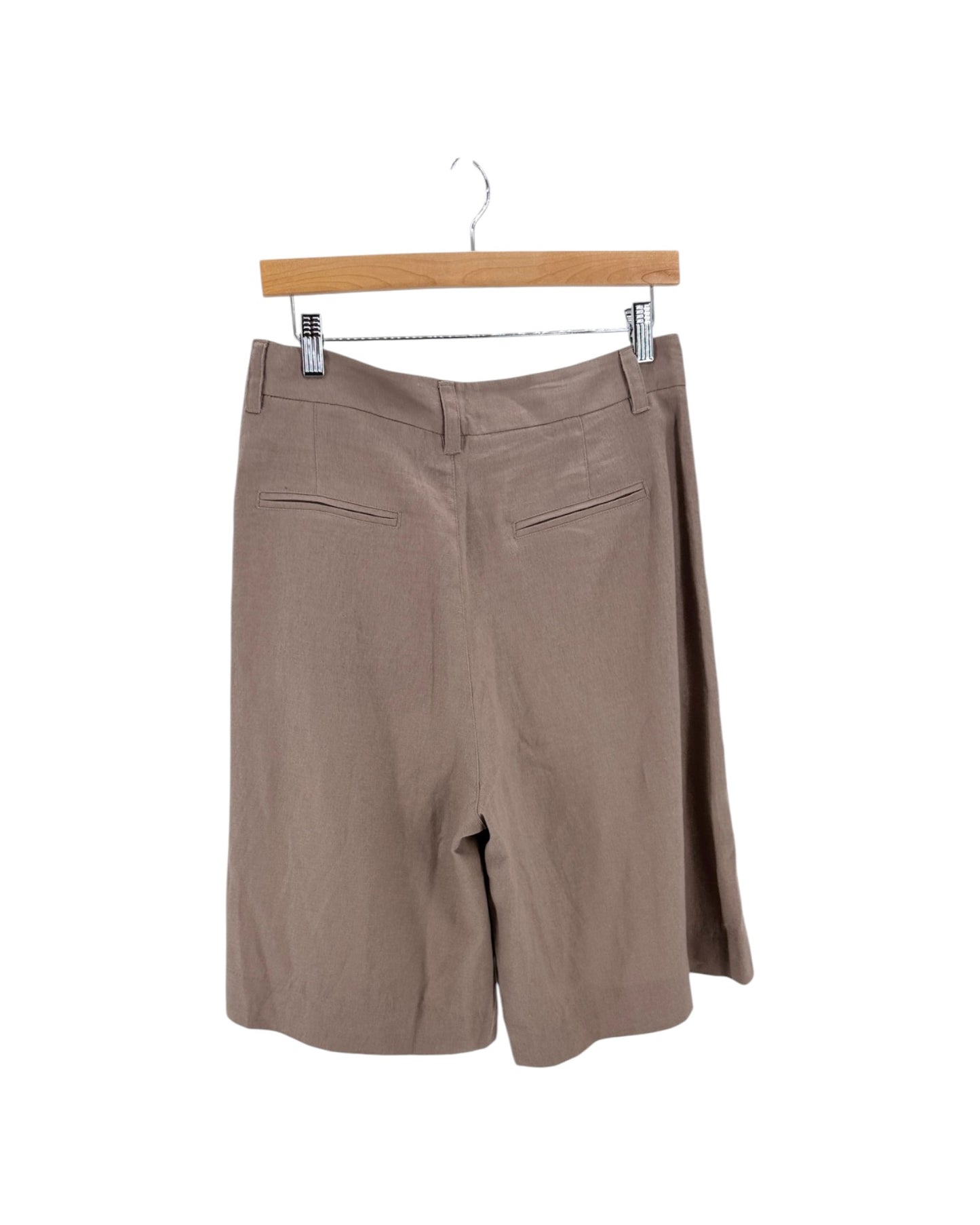 A pair of taupe brown wide-leg shorts hanging from a wooden hanger with metal clips against a plain white background.