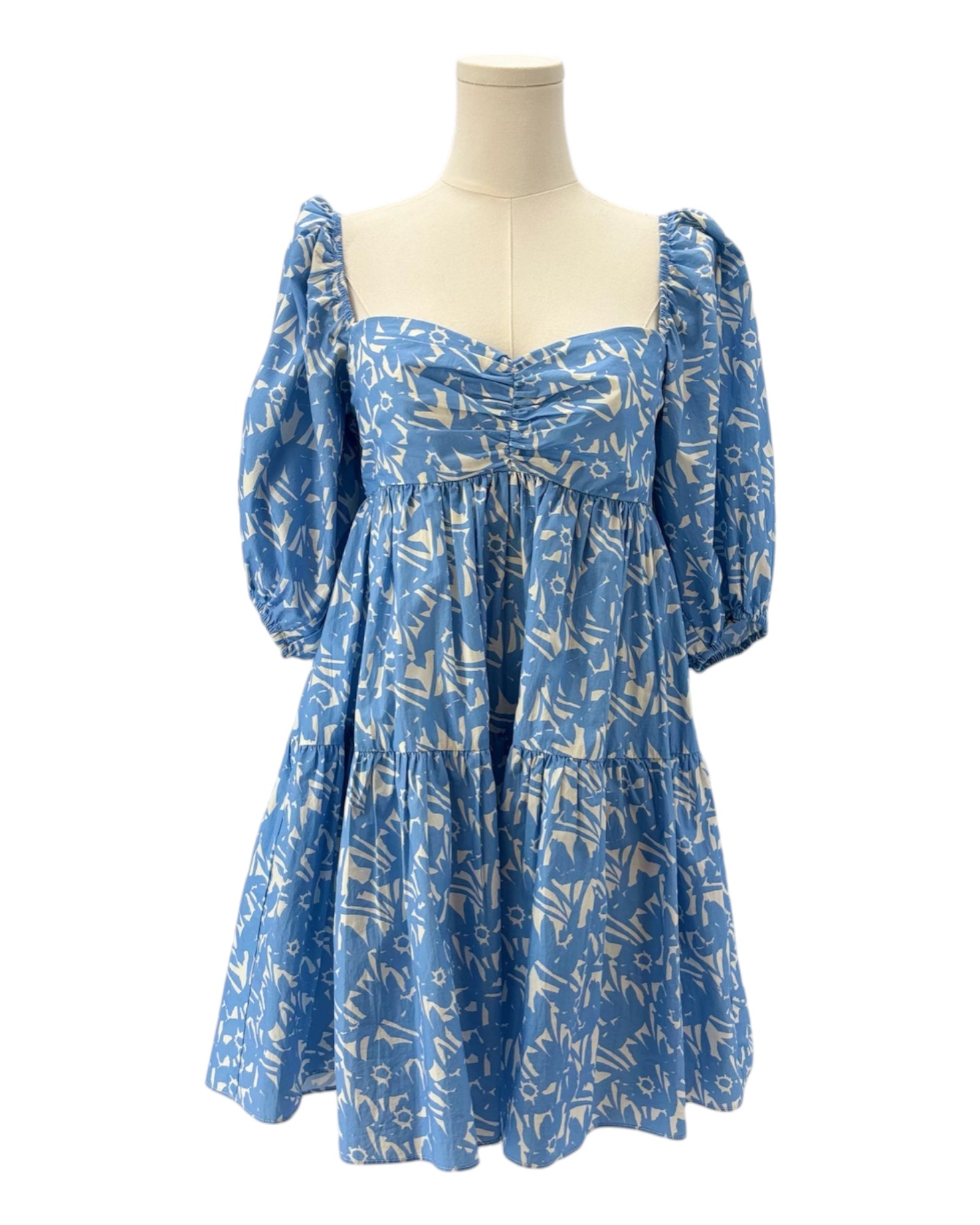 Blue dress with white pattern on a mannequin against a white background