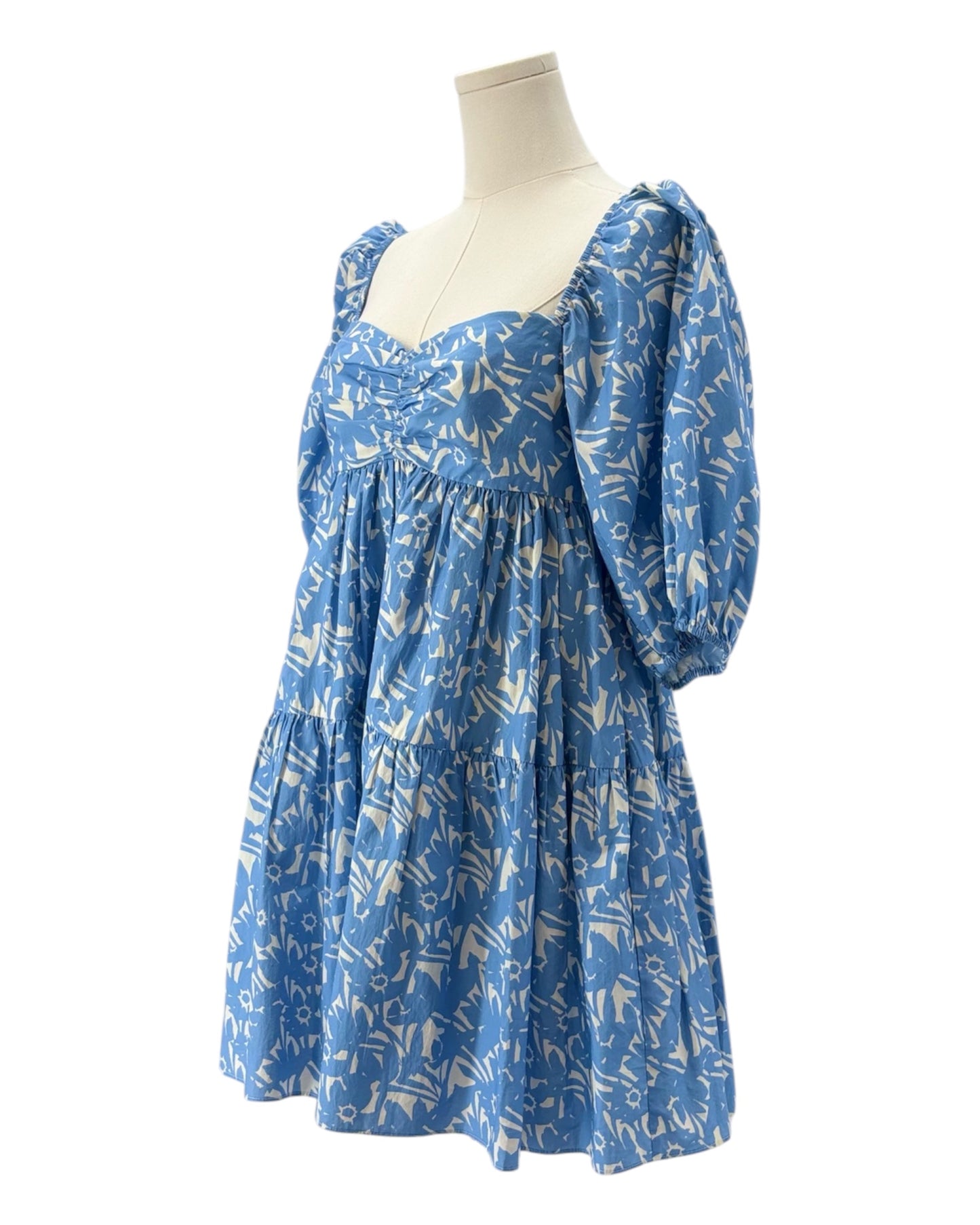 Blue dress with white floral pattern on a mannequin against a white background