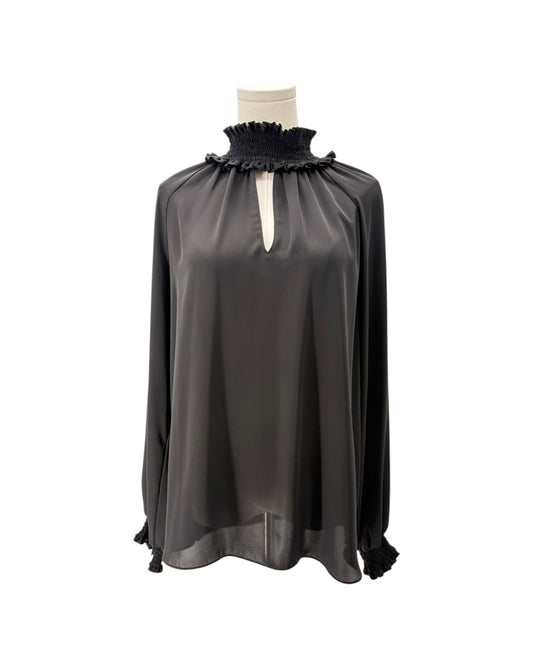 A black long-sleeve blouse with a ruffled mock neck and tassel ties, displayed on a mannequin torso against a white background.