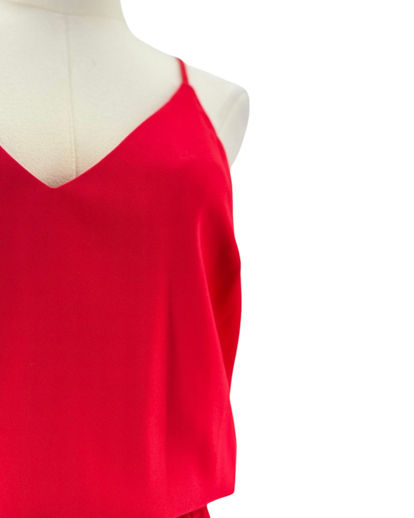 A bright red spaghetti-strap jumpsuit displayed on a cream mannequin torso against a plain white background.
