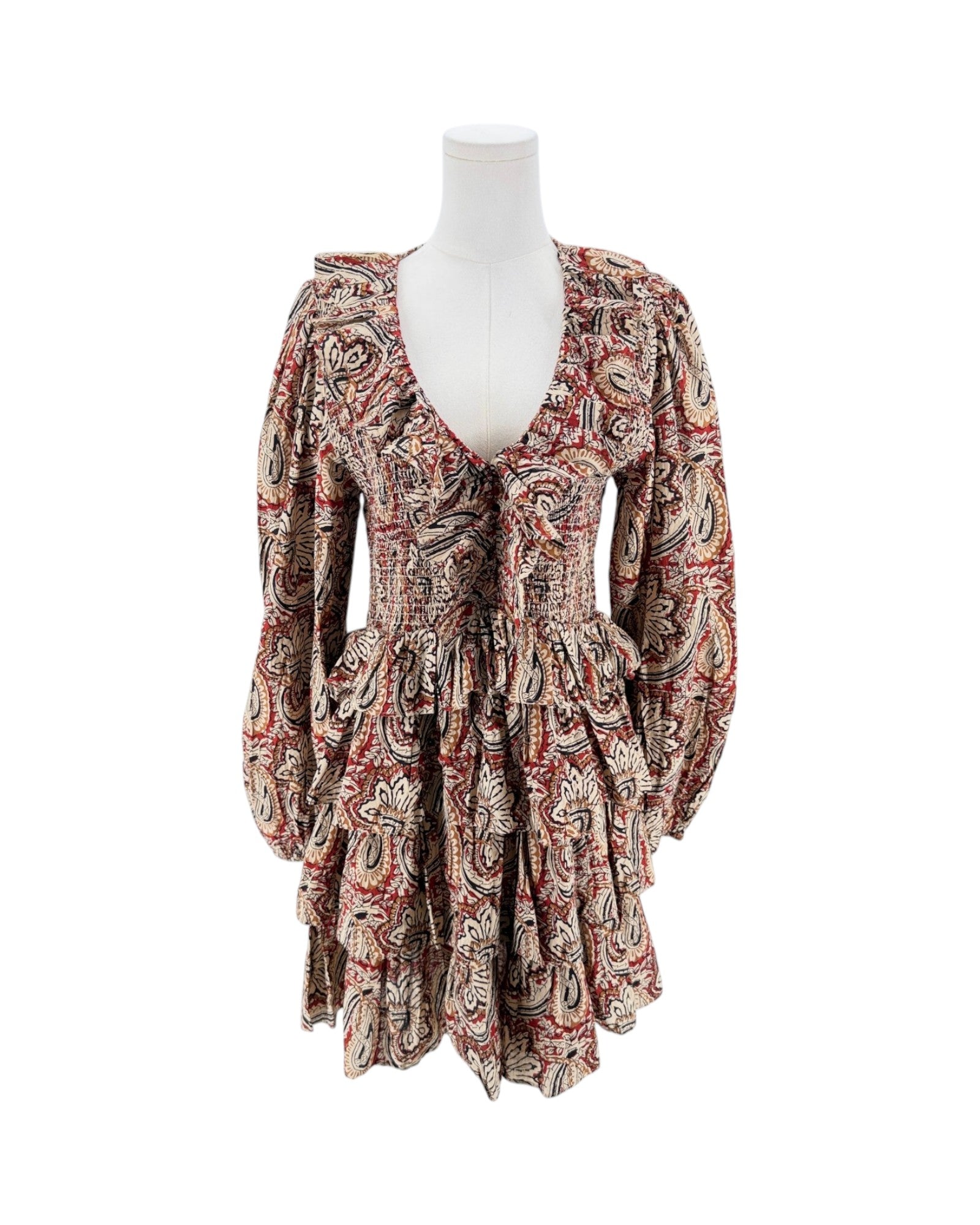 A long-sleeve mini dress with a deep V-neck and a busy paisley pattern in red, beige, and black, displayed on a white mannequin torso against a plain white background.