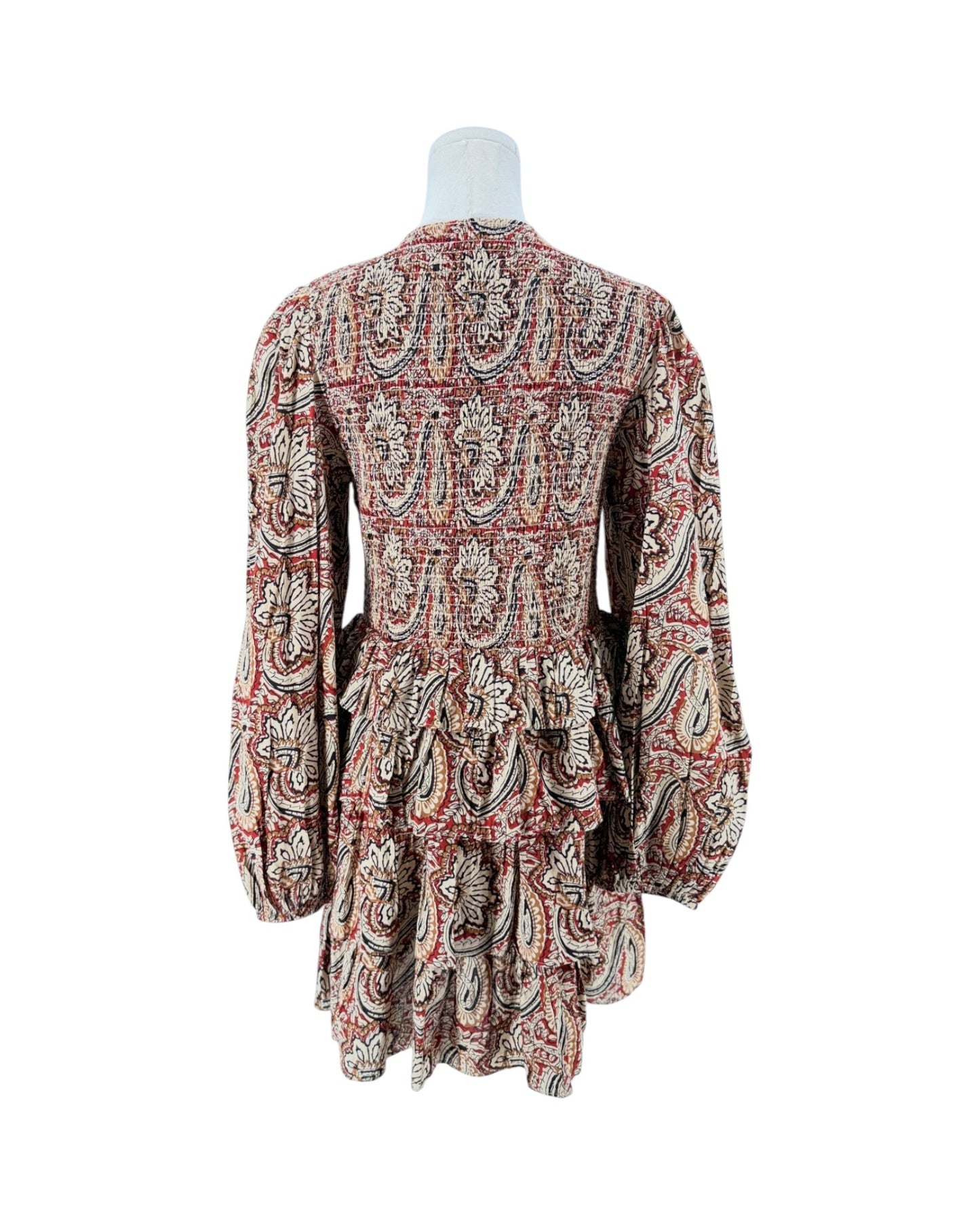 A long-sleeve mini dress with a deep V-neck and a busy paisley pattern in red, beige, and black, displayed on a white mannequin torso against a plain white background.