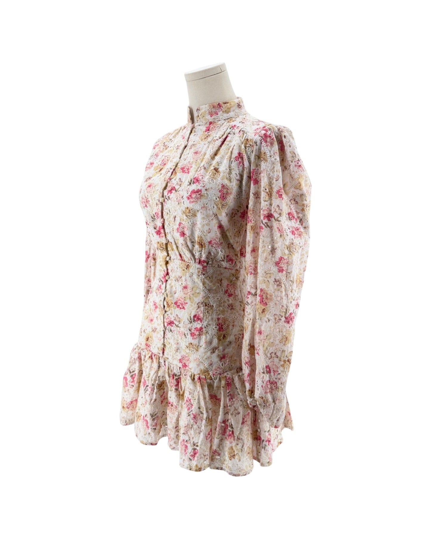 A vintage-style long-sleeve dress with a pink and yellow floral print on a cream background, displayed on a mannequin torso against a white background.
