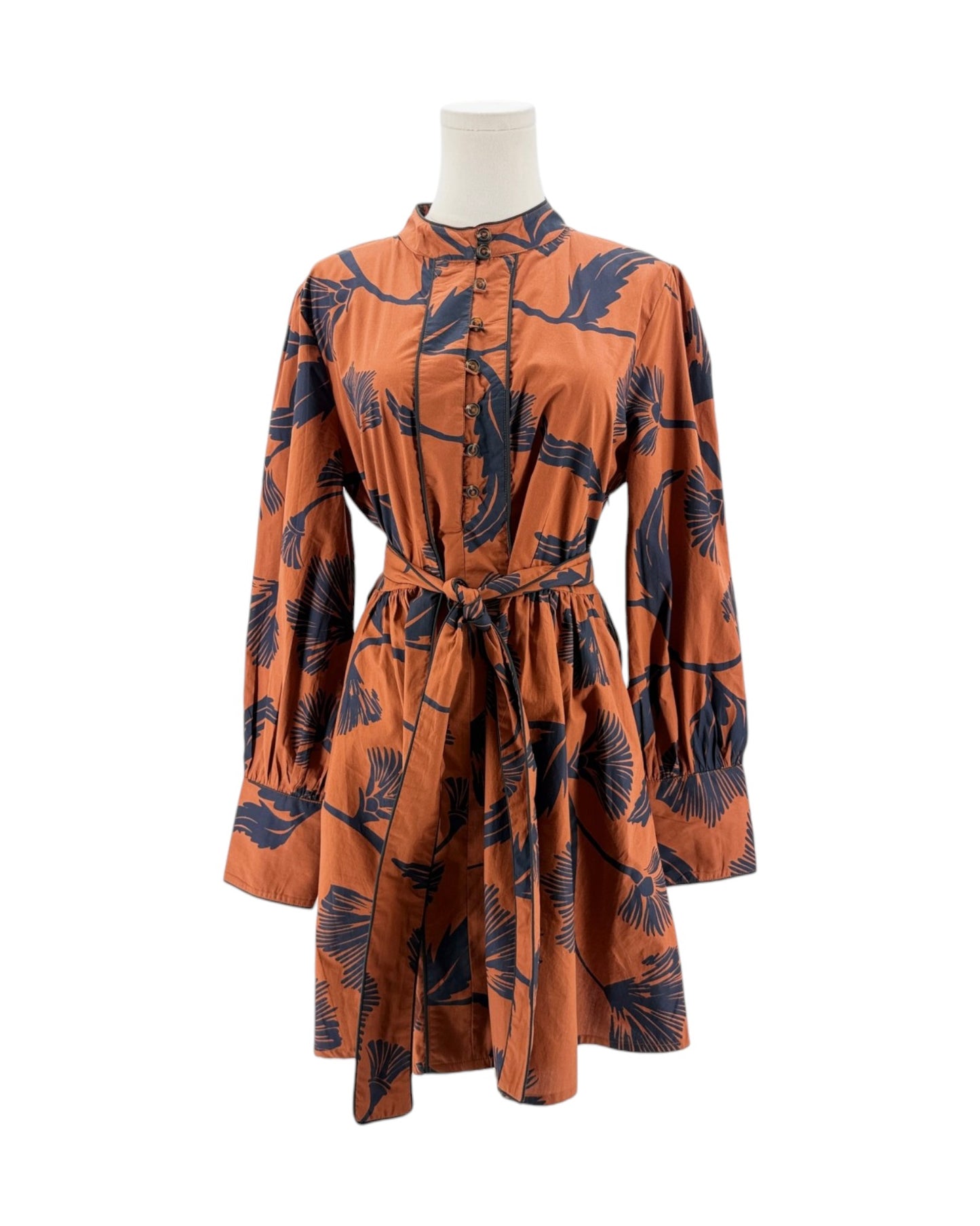 Orange dress with black leaf pattern on a mannequin against a white background