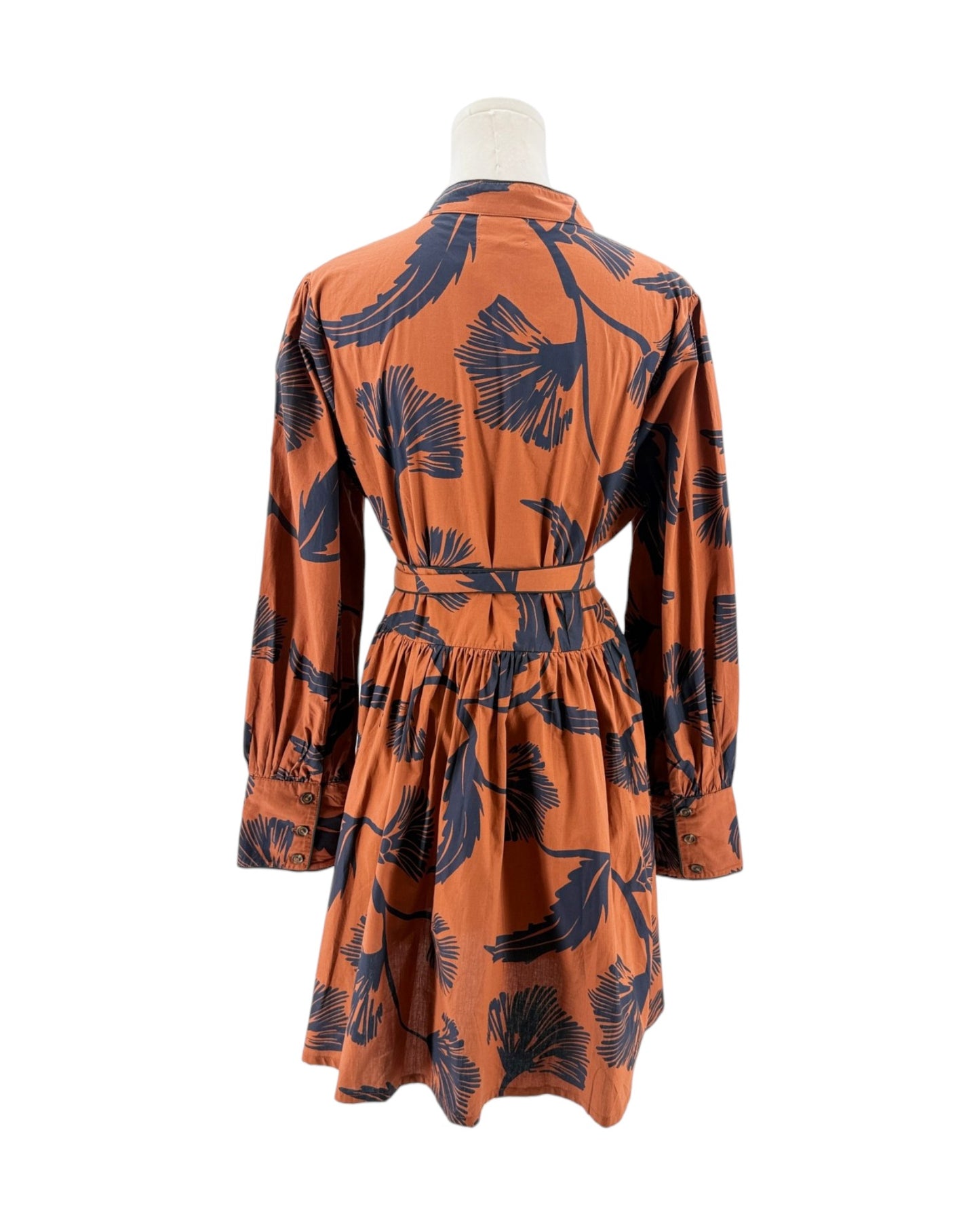 Orange dress with black leaf pattern on a mannequin against a white background