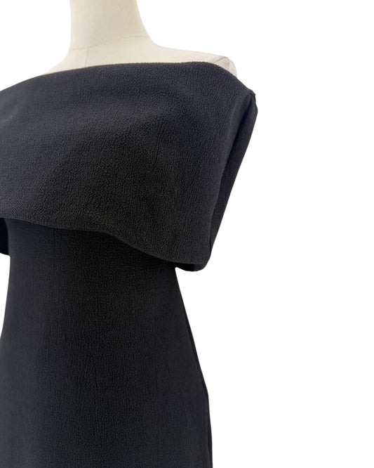Black off-the-shoulder neckline, crinkled jersey fabric, midi length dress on a mannequin on a white background