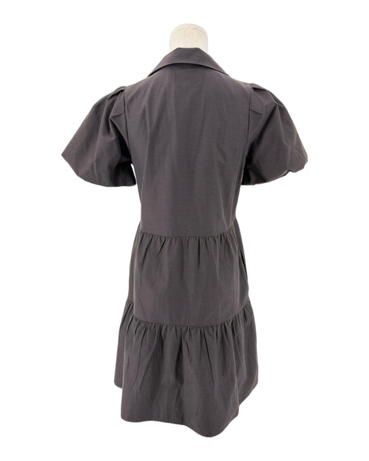 A black short-sleeve dress shown from the back on a mannequin, featuring a pointed collar, puffed sleeves, and a tiered waist.