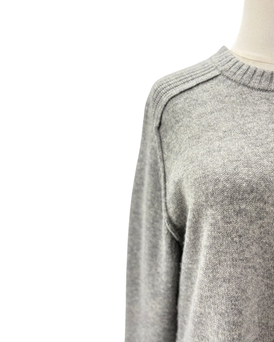 Close-up of a light gray knit sweater on a mannequin torso against a white background.