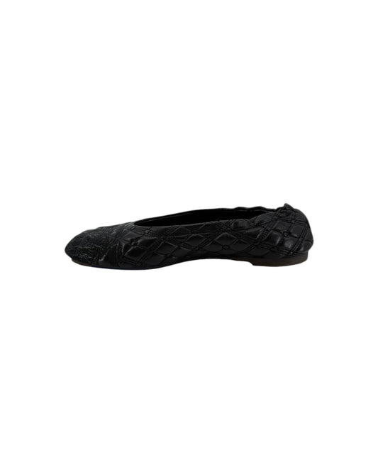 A single black ballet flat shoe with a textured quilted pattern, shown in profile against a plain white background.