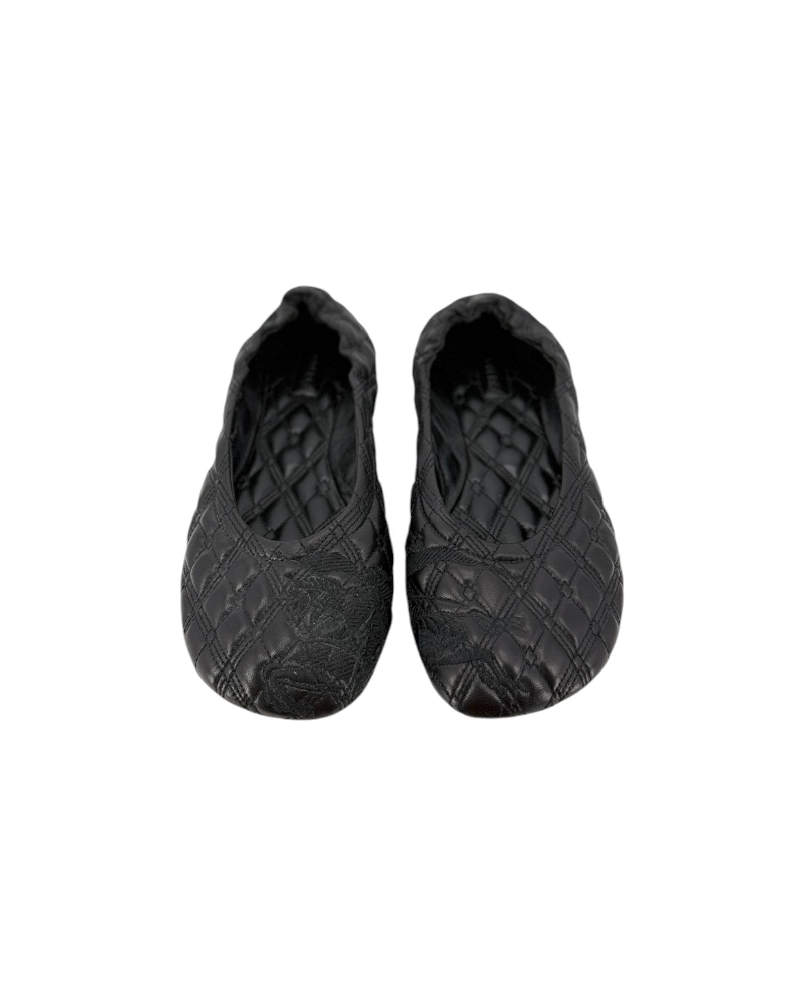 A pair of black quilted slip-on shoes with a textured, embossed pattern, shown against a plain white background.