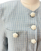 Close-up of a textured blue and gray jacket with decorative buttons on a mannequin.